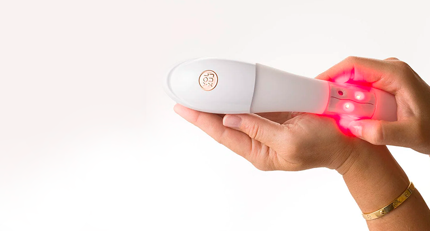 A hand holding a white handheld laser therapy device emitting red light for pain relief and tissue repair. Advancements in Regenerative Medicine Research and Education
